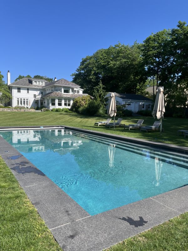 picture of a pool in front of a white mansion